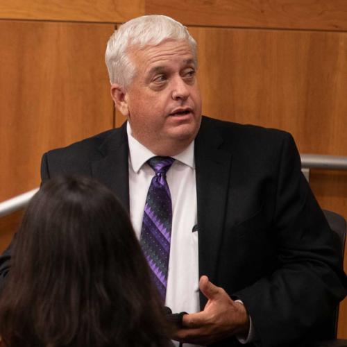 Len Reid-Reynoso, man in suit in front of paneling