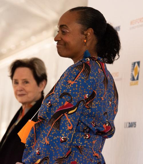 2 women on podium, preparing to speak.