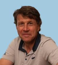 Smiling man in striped polo against light blue background (photograph)