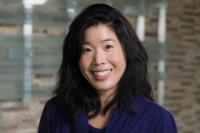 Woman with black hair and a blue shirt smiling at camera.