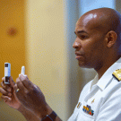 Physician in U.S. Public Health Service uniform, holds up two medications.niform