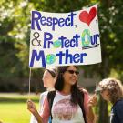 Woman at Climate Action Strike, holding sign encouraging people to respect, love and protect our Mother Earth