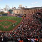 Wide-angle photo of a sold-out game at Oriole Park at Camden Yards. The view is from behind home plate, high up in the stands. The left and right field stands are seen.