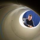 Simon Cherry framed inside the open end of a large white pipe, a PET scanner