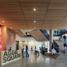 Bright modern lobby featuring a colorful mural, wooden accents, and people interacting.