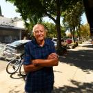 Man stands on street with arms folded in front