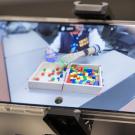 A smartphone displays a hands-on activity with colorful blocks on a table.