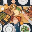 Food on a table with hands reaching across