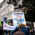 Protesters carry signs with word "love" crossed out and "CO2 Is in the Air" written on it