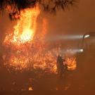 Firefighters and heavy equipment with fire in background