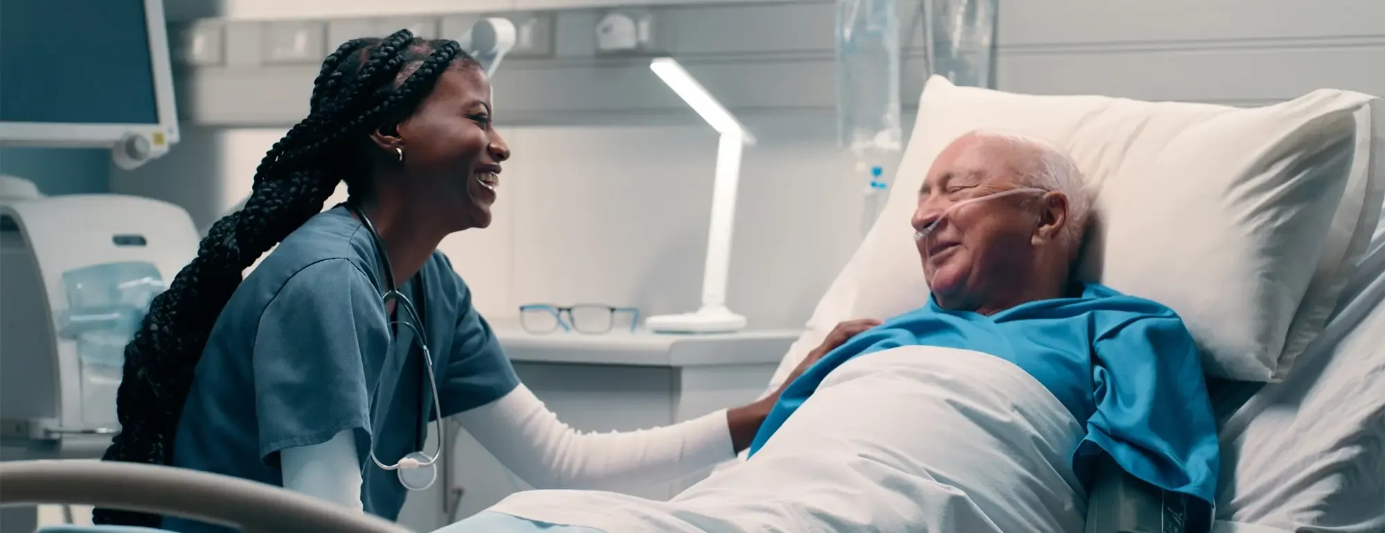 A doctor or nurse caring for a patient who is lying in bed in a hospital room