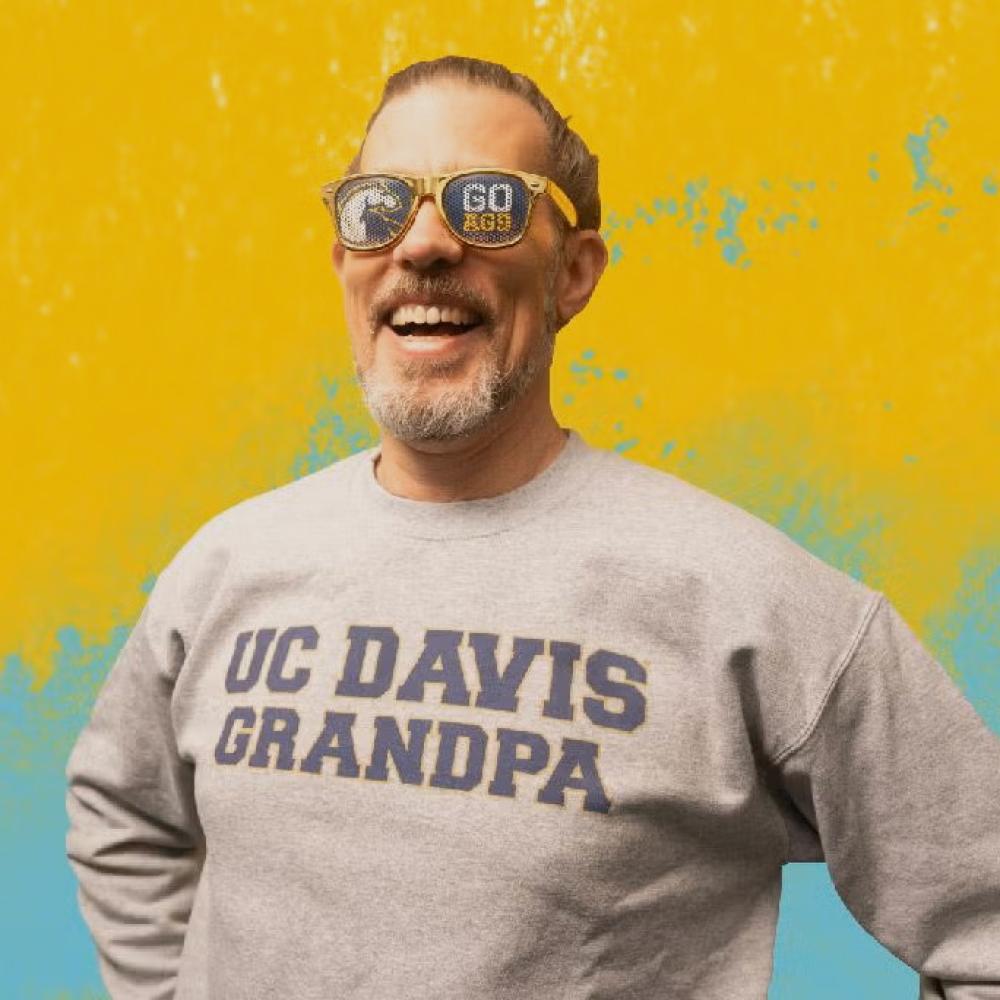 a person wearing a UC Davis branded sweatshirt in front of a yellow background